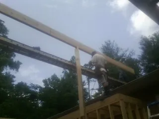 Carpenter setting a ridge beam over a new addition frame — Ice Dam Removal by Roofing Brothers in Carrsville