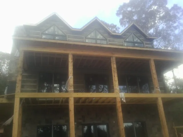 Dormers and porch framing on a large log home under construction — Roof Coating work by our crew in Carrsville