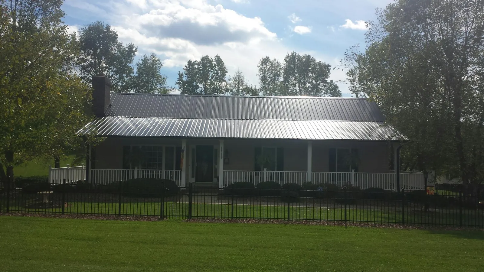 Gray metal roof on a brick ranch with a full width front porch — Gutter Guard Installation work by our crew in Carrsville
