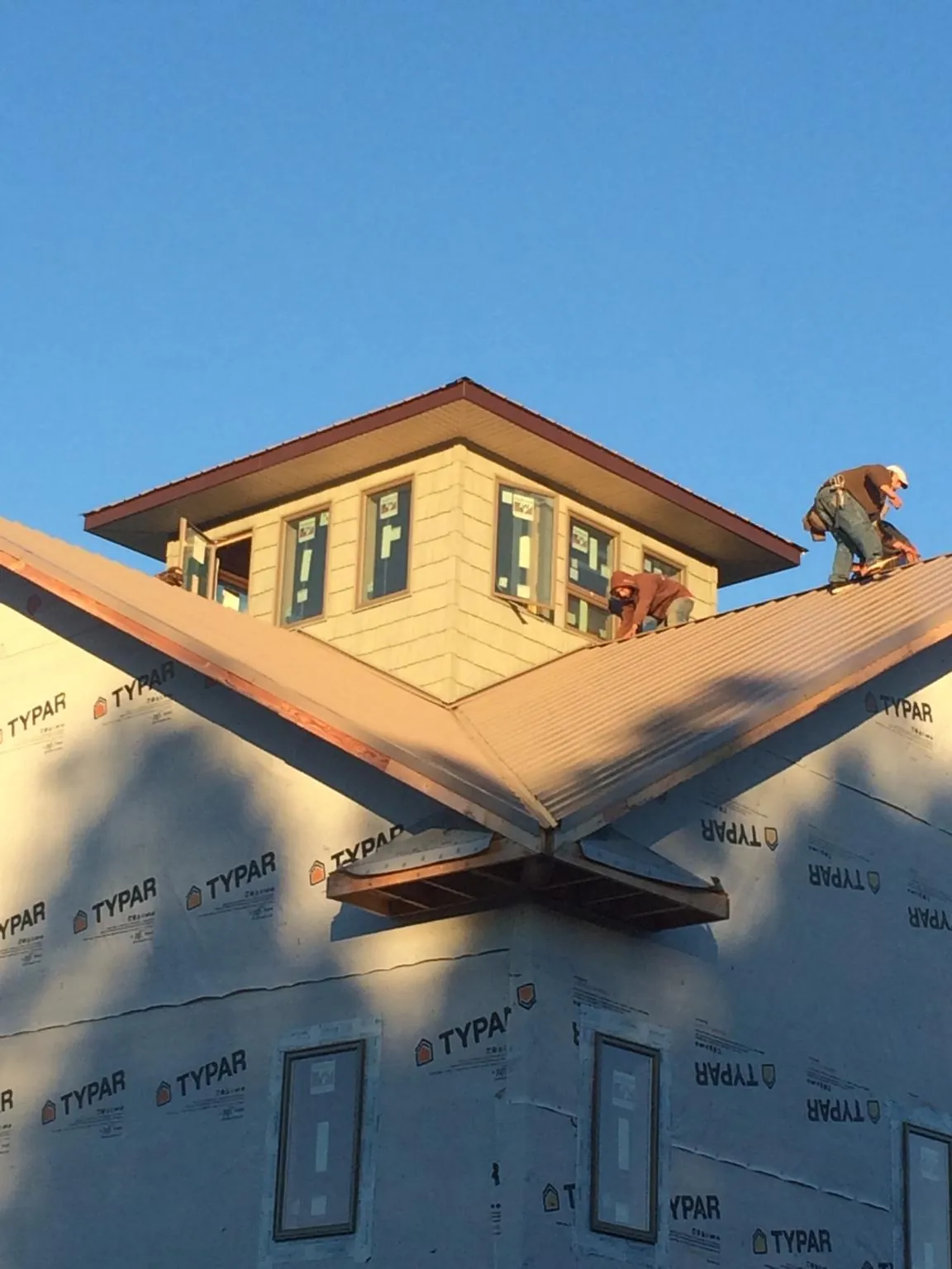 Roofers working around a rooftop cupola on a new metal roof at sunset — Roof Waterproofing in Carrsville by Roofing Brothers